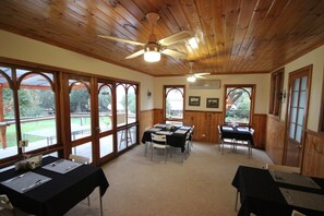 Enjoy a spacious room with high ceilings, wooden beams, and large windows offering views of the outdoors.