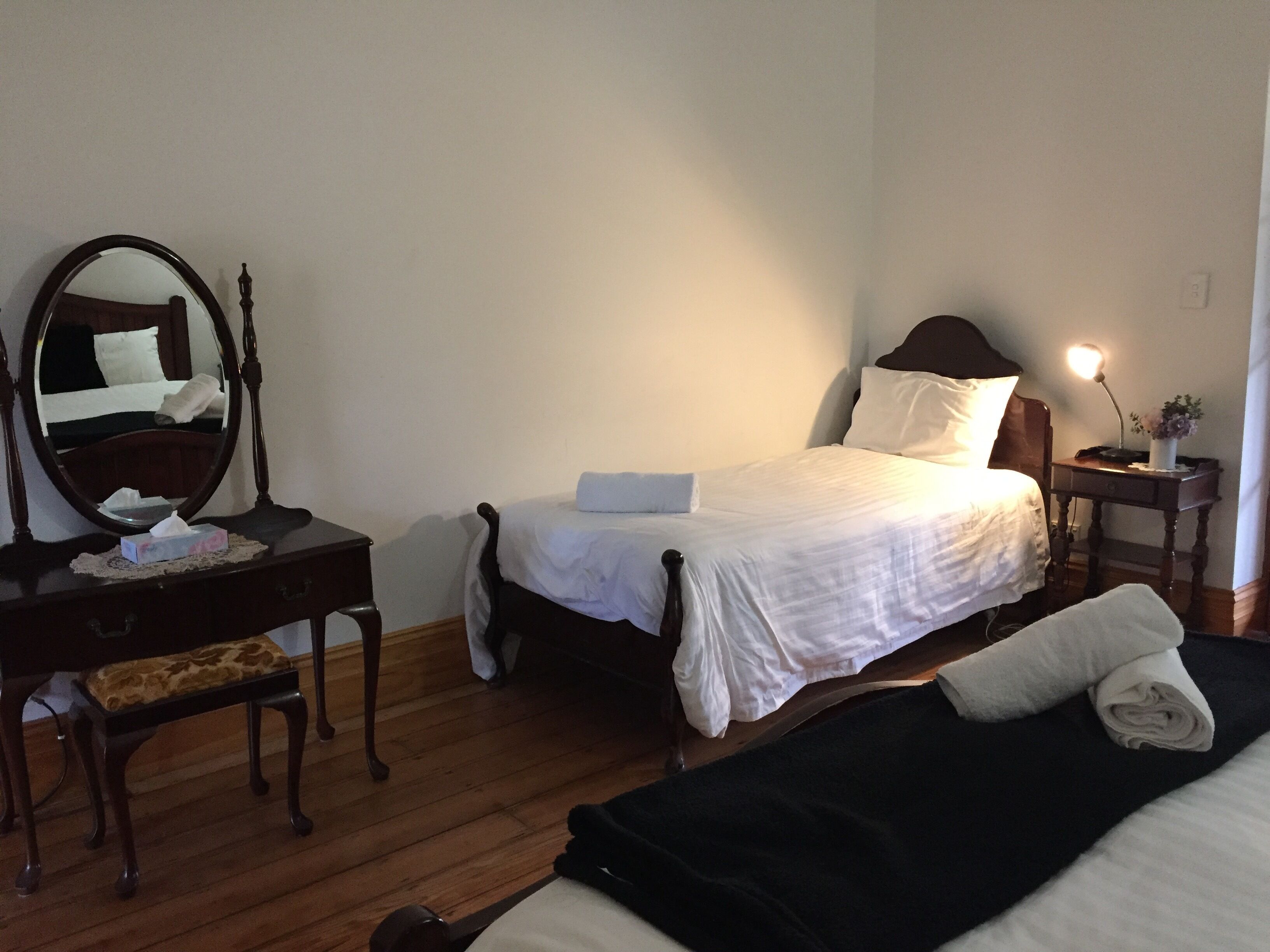 A hotel room with a bed, bedside table, lamp, and a mirror.