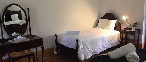 A hotel room with a bed, bedside table, lamp, and a mirror.