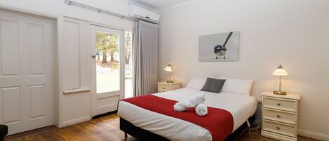 Un dormitorio ordenado con una cama grande, dos mesitas de noche y un ventilador de techo.