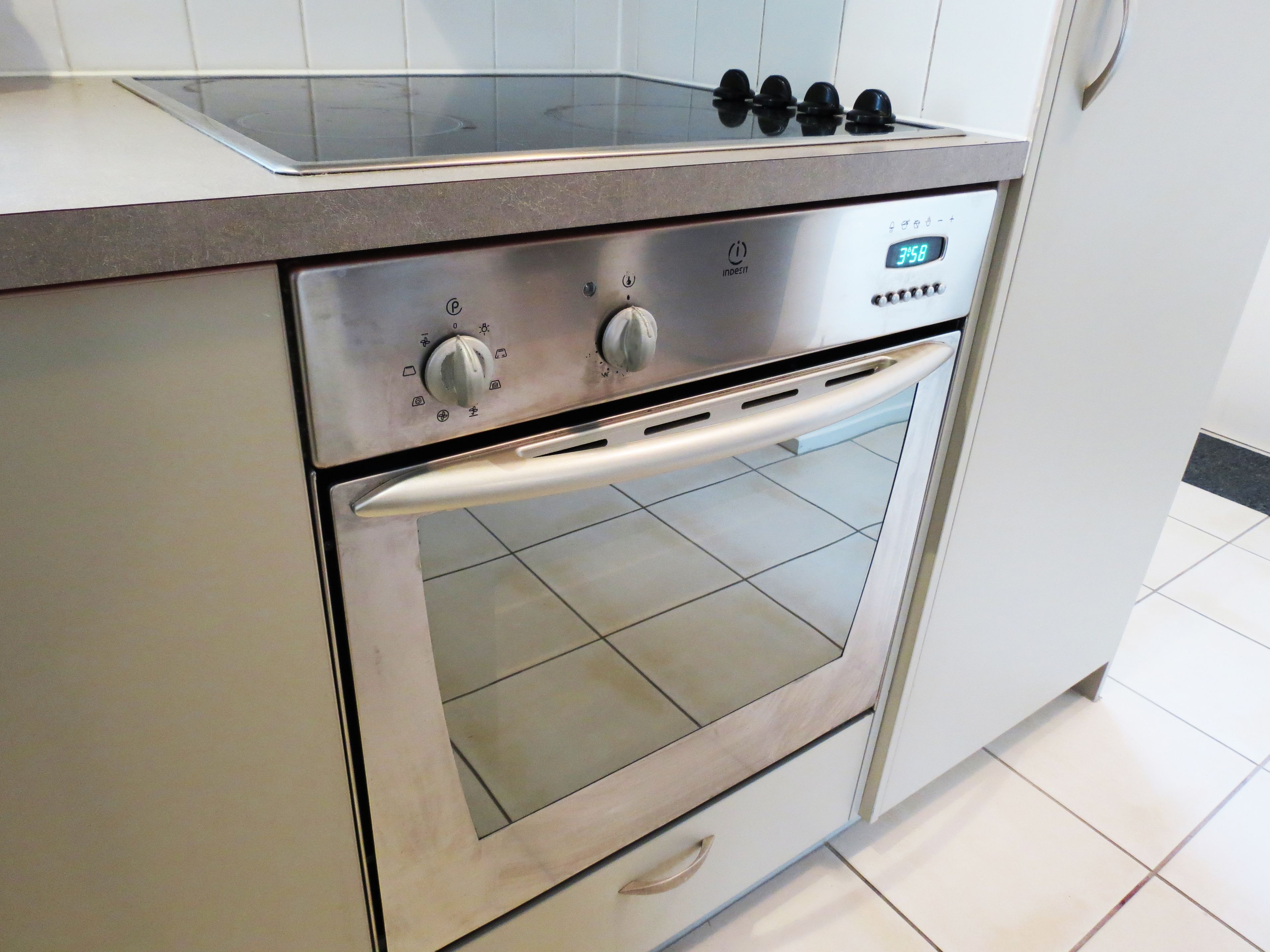 Un horno de acero inoxidable con un reloj digital que muestra las 3:58, un panel de control con perillas y un tirador de acero inoxidable.