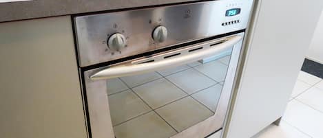 Un horno de acero inoxidable con un reloj digital que muestra las 3:58, un panel de control con perillas y un tirador de acero inoxidable.