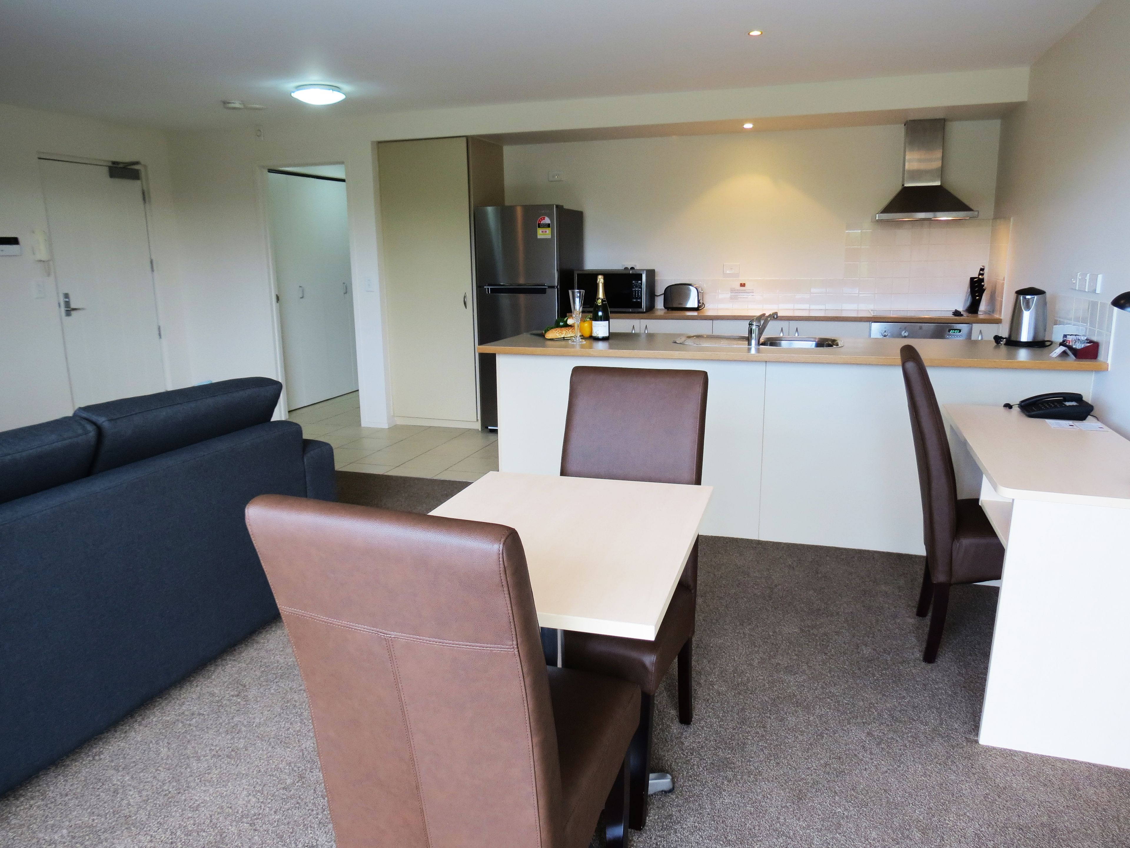 A compact living space with a kitchenette, a dining area with a table and chairs, and a sofa.