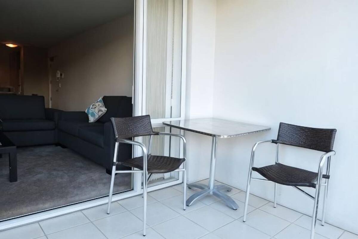 Una habitación pequeña con un sofá, dos sillones, una mesa y un ventanal grande.