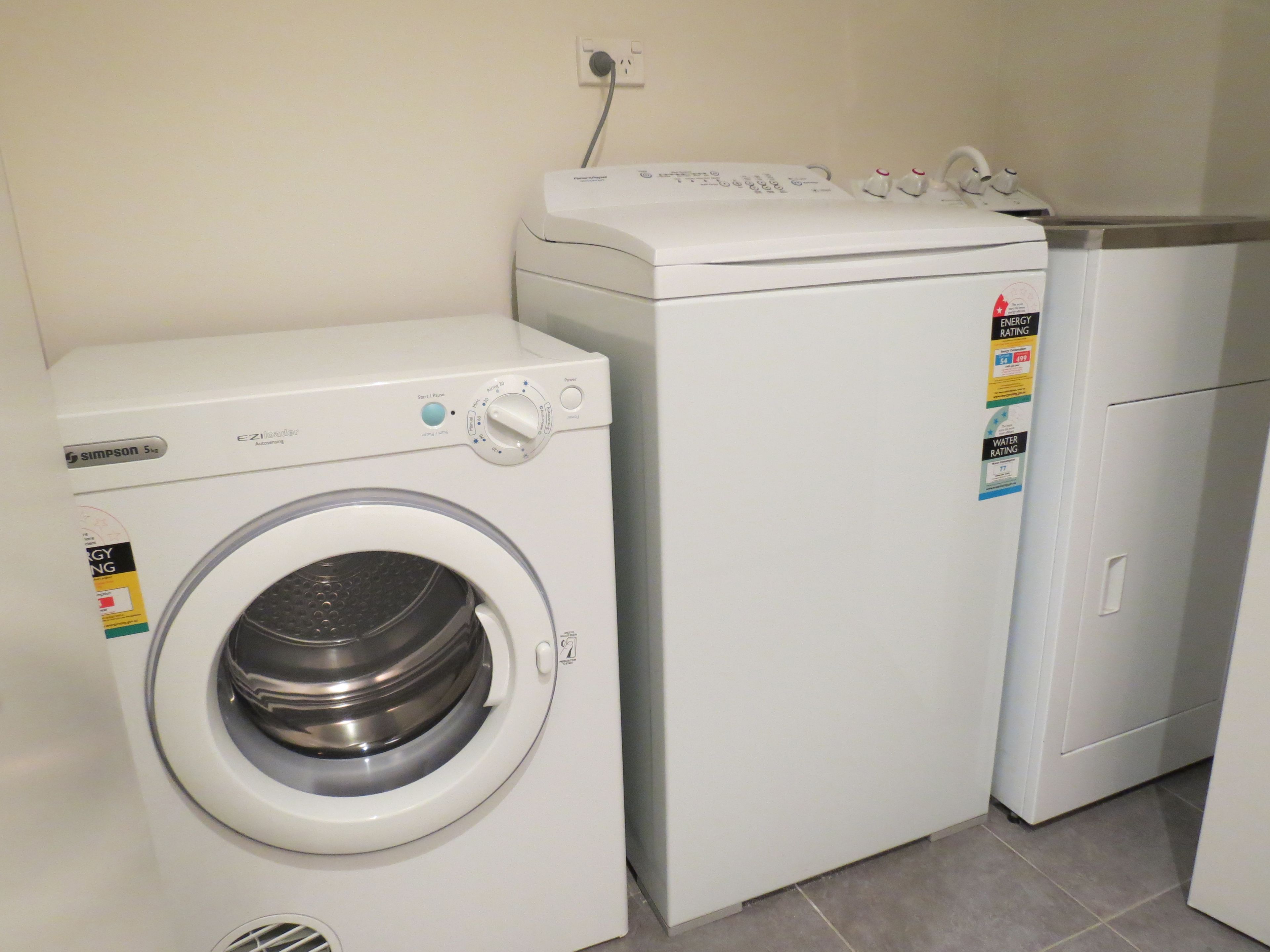 A compact laundry area with a front-loading washing machine and a small refrigerator.
