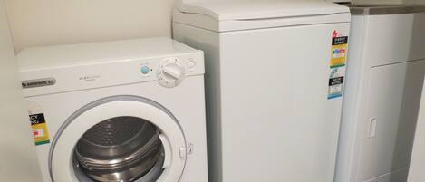 A compact laundry area with a front-loading washing machine and a small refrigerator.