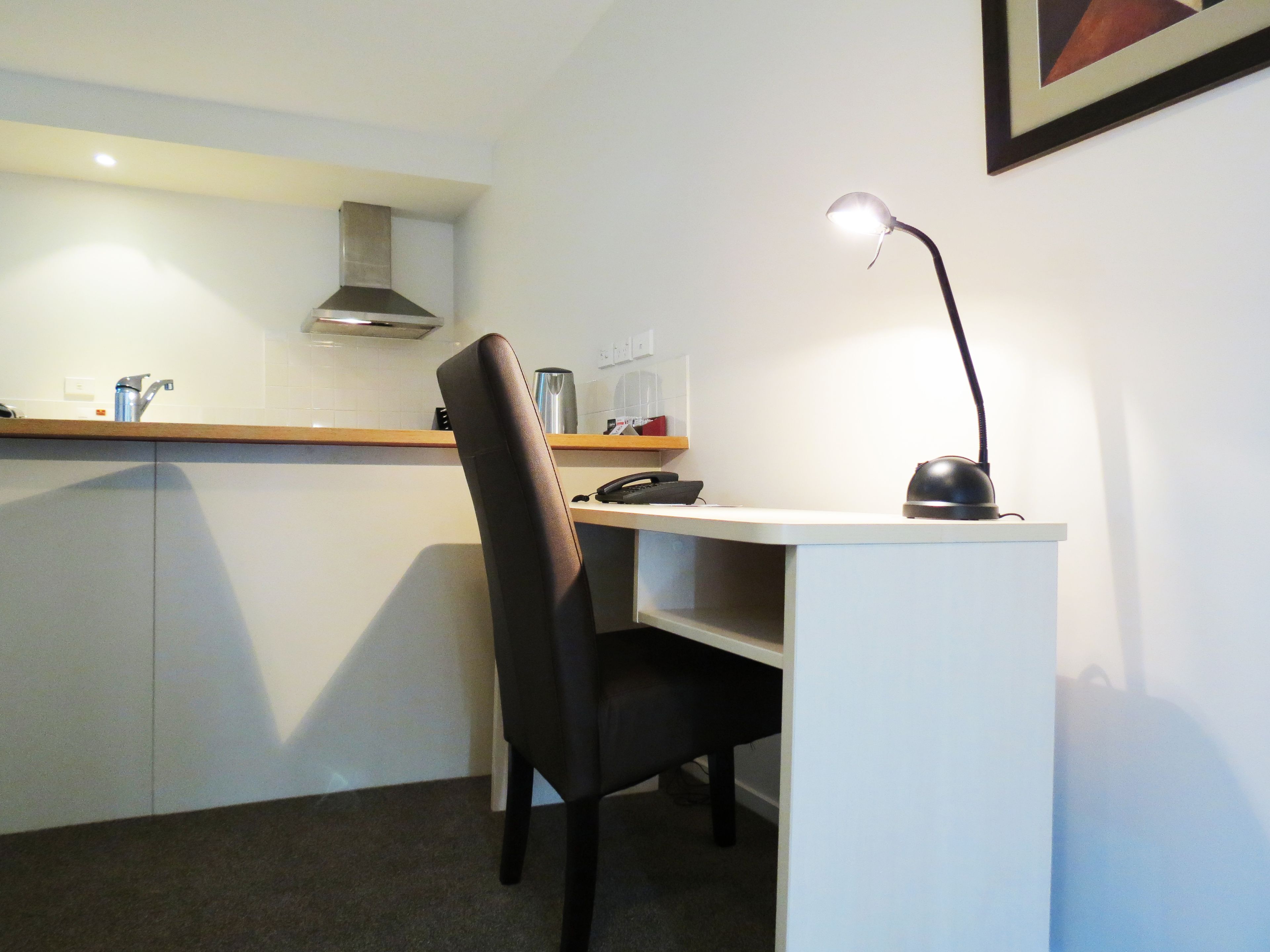 Un petit bureau moderne, équipé d’un bureau, d’une chaise et d’une lampe de bureau.