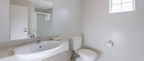 A bathroom with a white sink, toilet, and mirror.