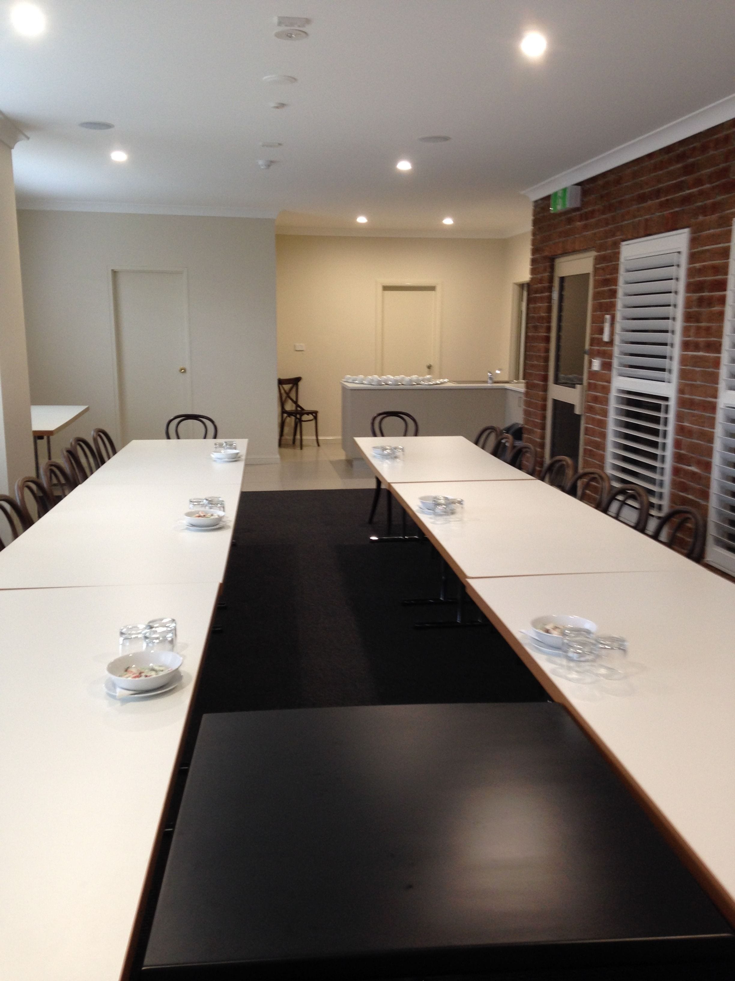 A conference room with long tables, chairs, and a brick wall.