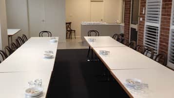 A conference room with long tables, chairs, and a brick wall.