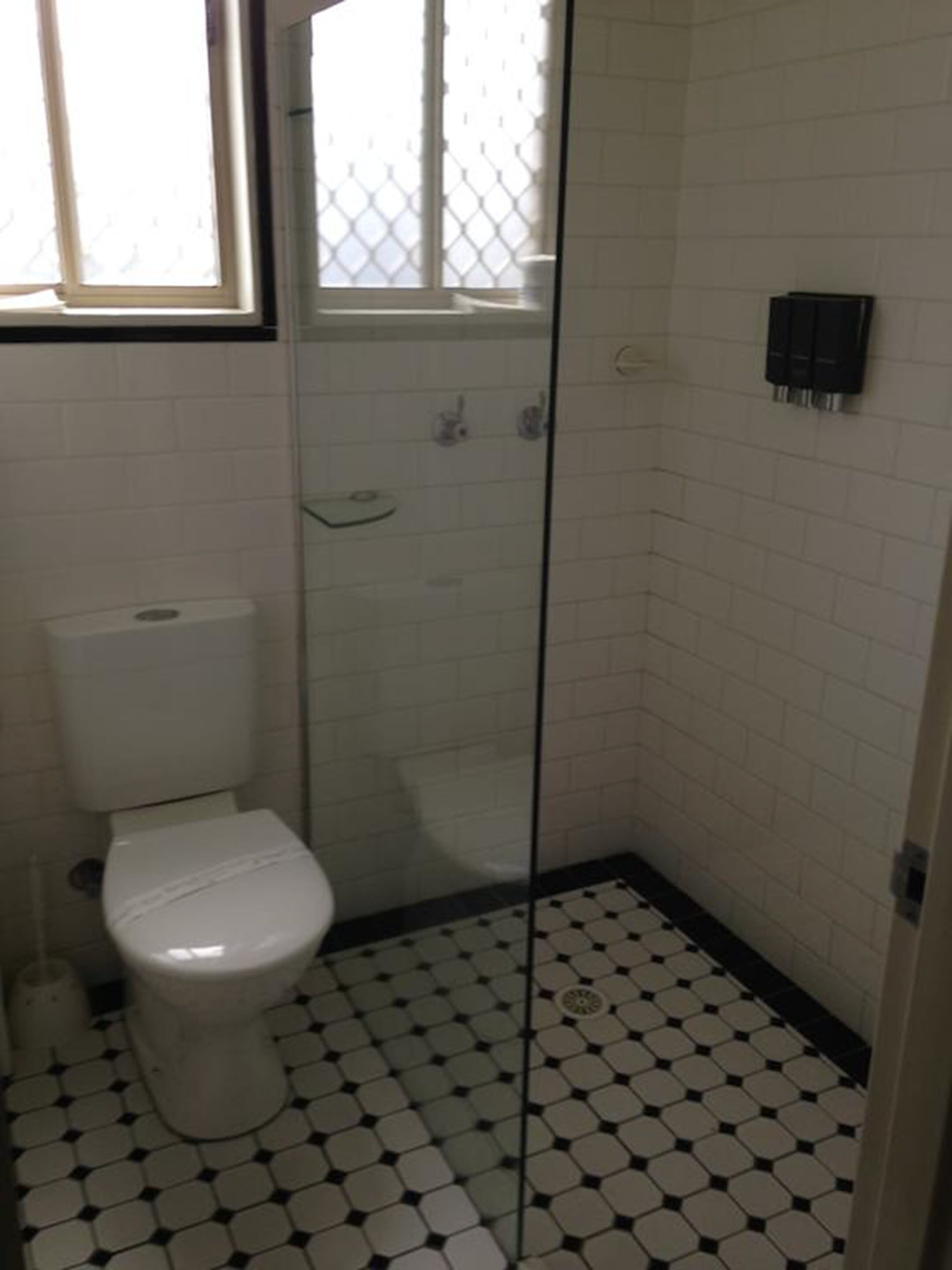 Une salle de bain avec des toilettes, une douche et un sol carrelé.