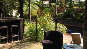 Un patio al aire libre con mobiliario de mimbre, incluyendo una silla y una mesita redonda.