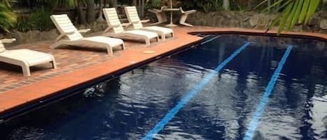 Una piscina al aire libre, sillones reclinables de piscina