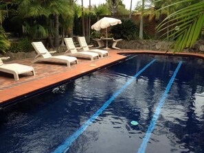 Una piscina al aire libre, sillones reclinables de piscina