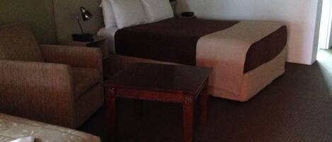 Una habitación de hotel con una cama, un sofá, una silla y una mesita.