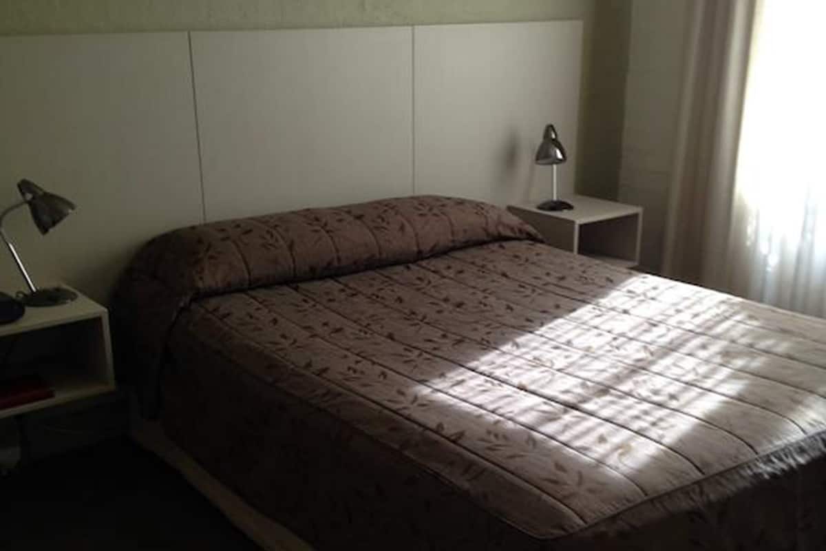 Un dormitorio con una cama grande, dos mesitas de noche y un buró.