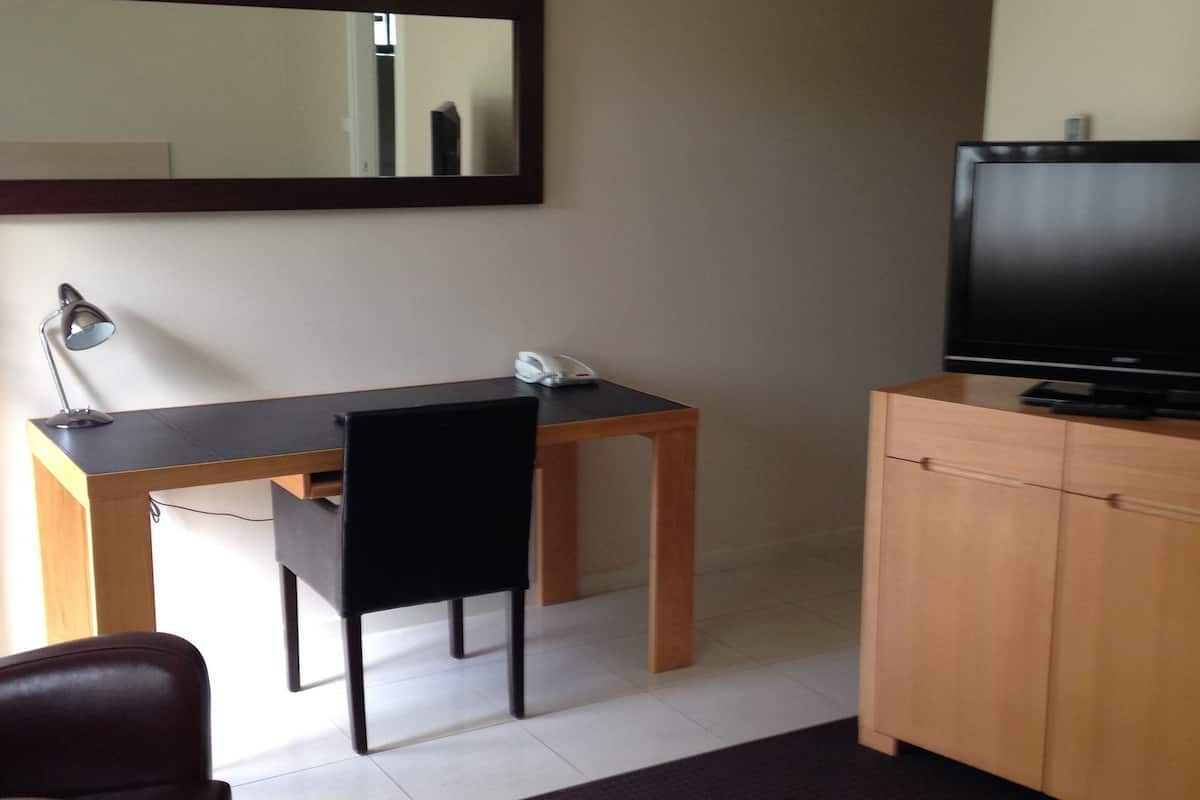 Una habitación de hotel con escritorio, silla, televisor y cama.