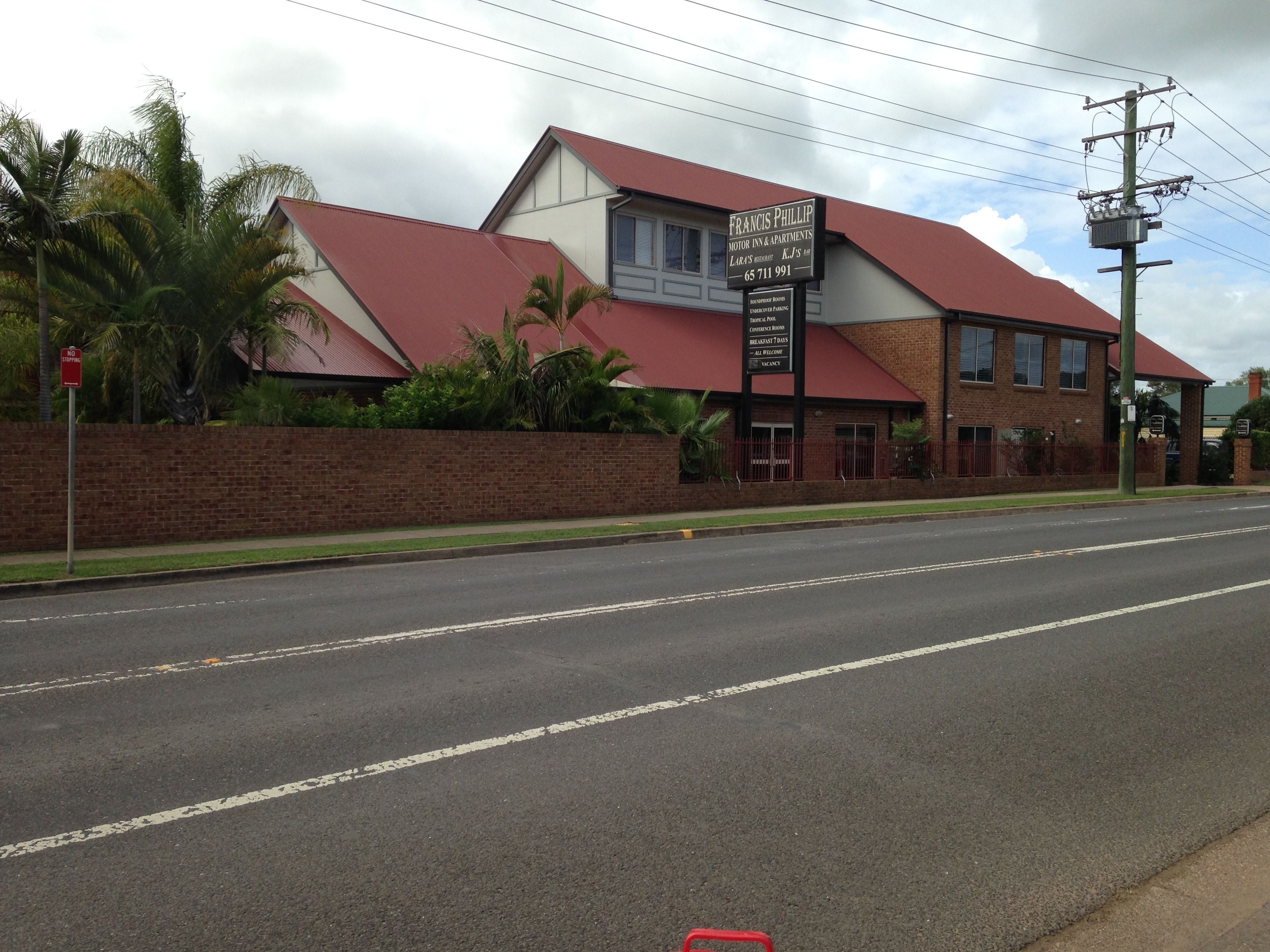 A building with a red roof and a sign advertising Francis Phillip Motor Inn & Apartments.