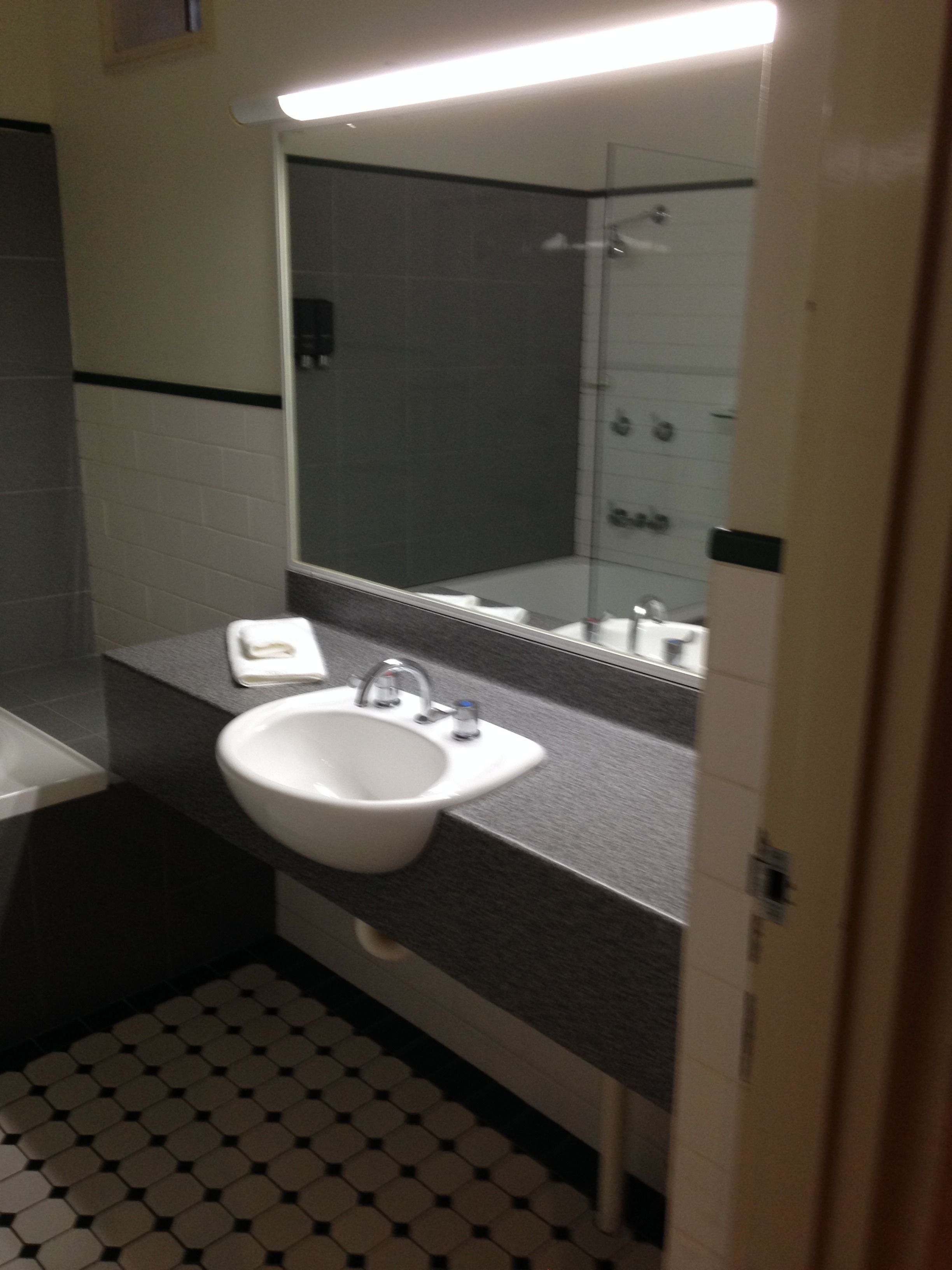 Une salle de bain avec un lavabo blanc, un miroir et une douche.