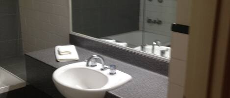 Une salle de bain avec un lavabo blanc, un miroir et une douche.
