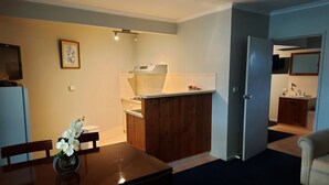 Un espace de vie compact comprenant un coin repas, une kitchenette et une petite salle de bain.