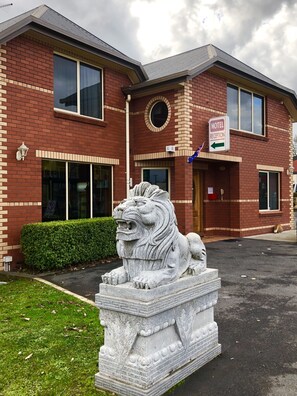 A brick building with a stone lion statue in front.