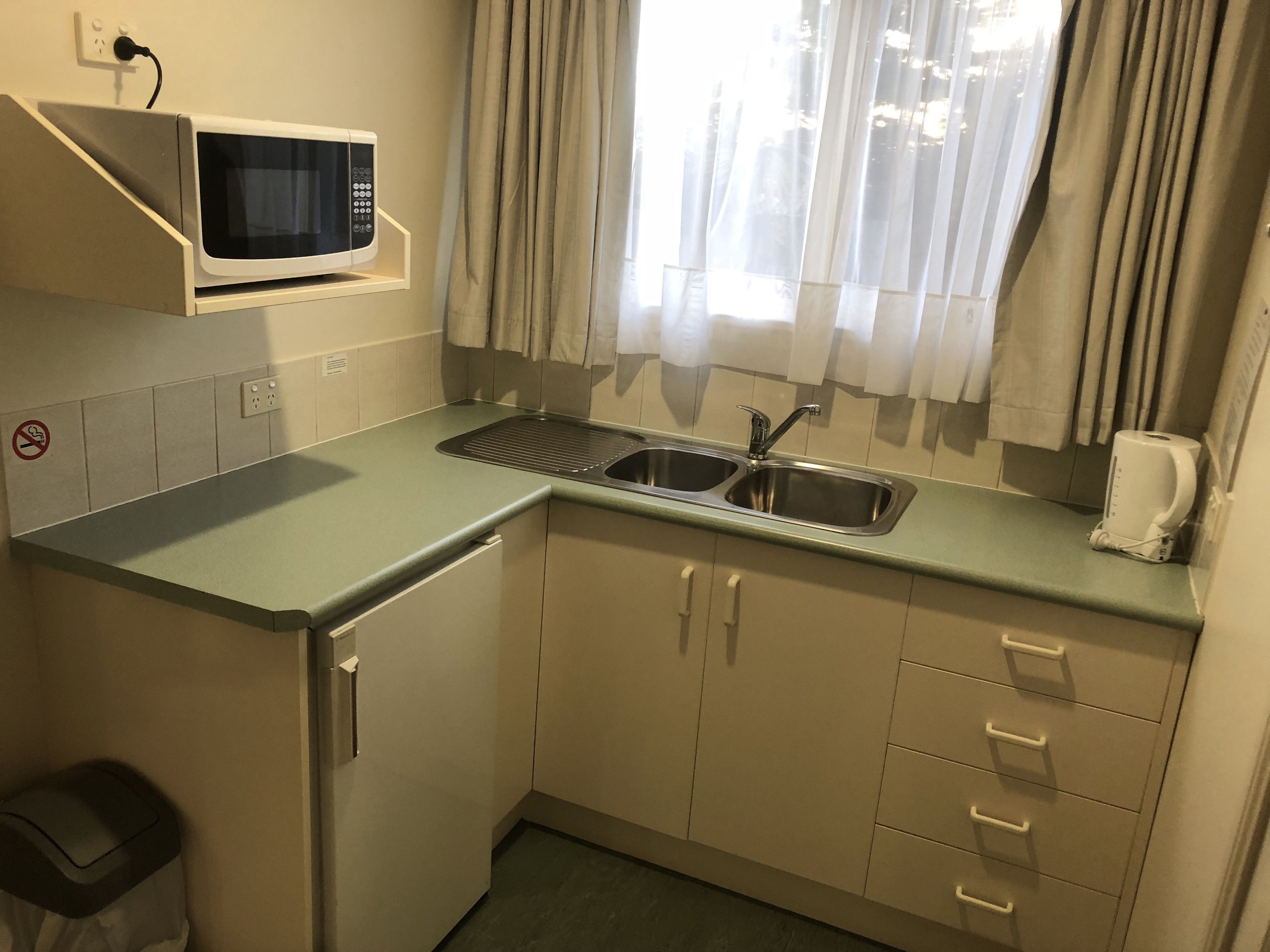 A compact kitchen with a microwave, sink, and cabinets.