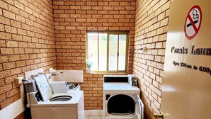 Una sala de lavandería con pared de ladrillo, una ventana y una puerta con un cartel de prohibido fumar.