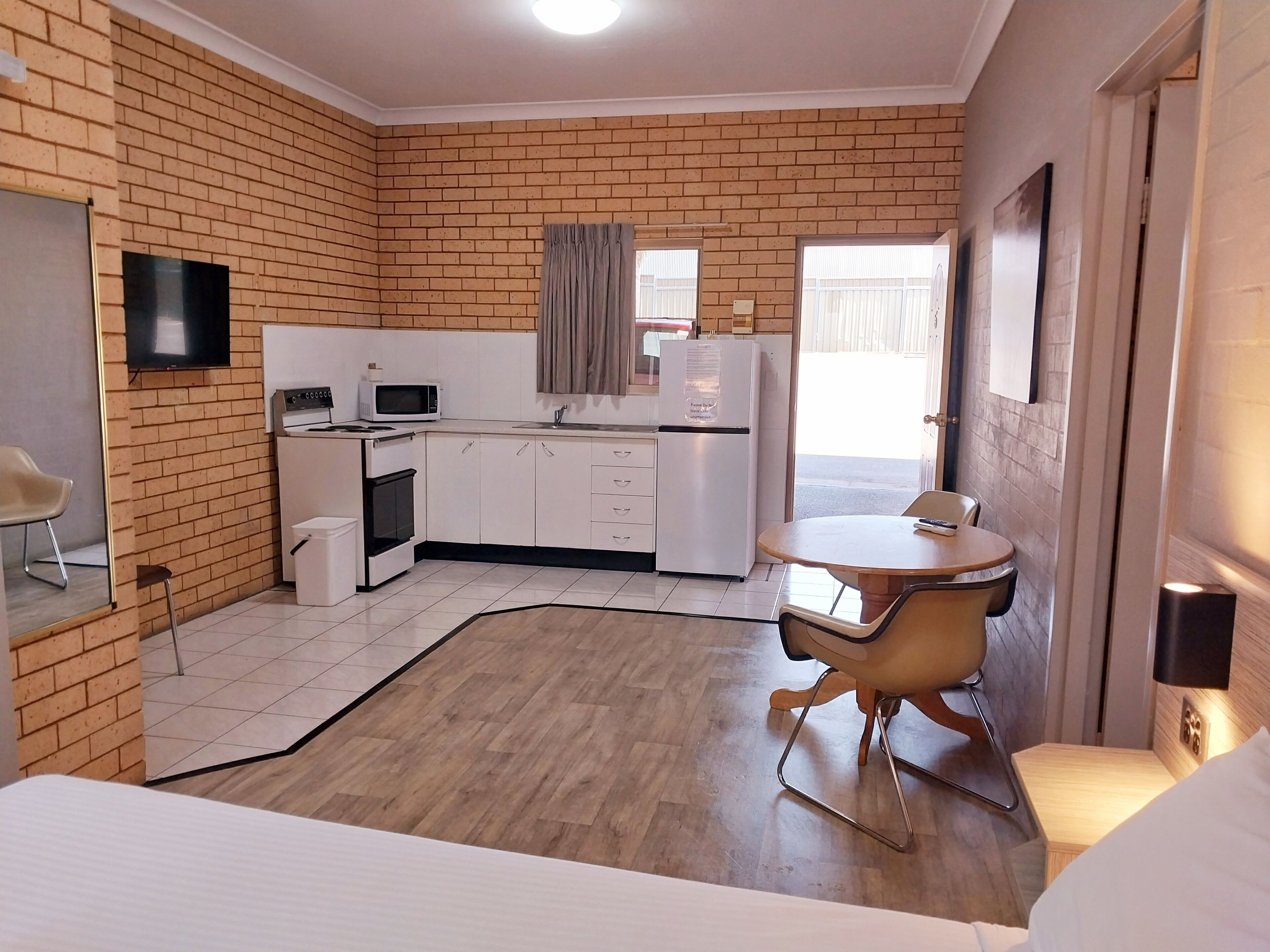 A compact hotel room with a kitchenette, a dining area, and a bed.
