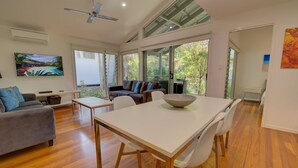 A spacious living area with a dining table, a sofa, and a TV. - Mobys Beachside Retreat (Boomerang Beach)