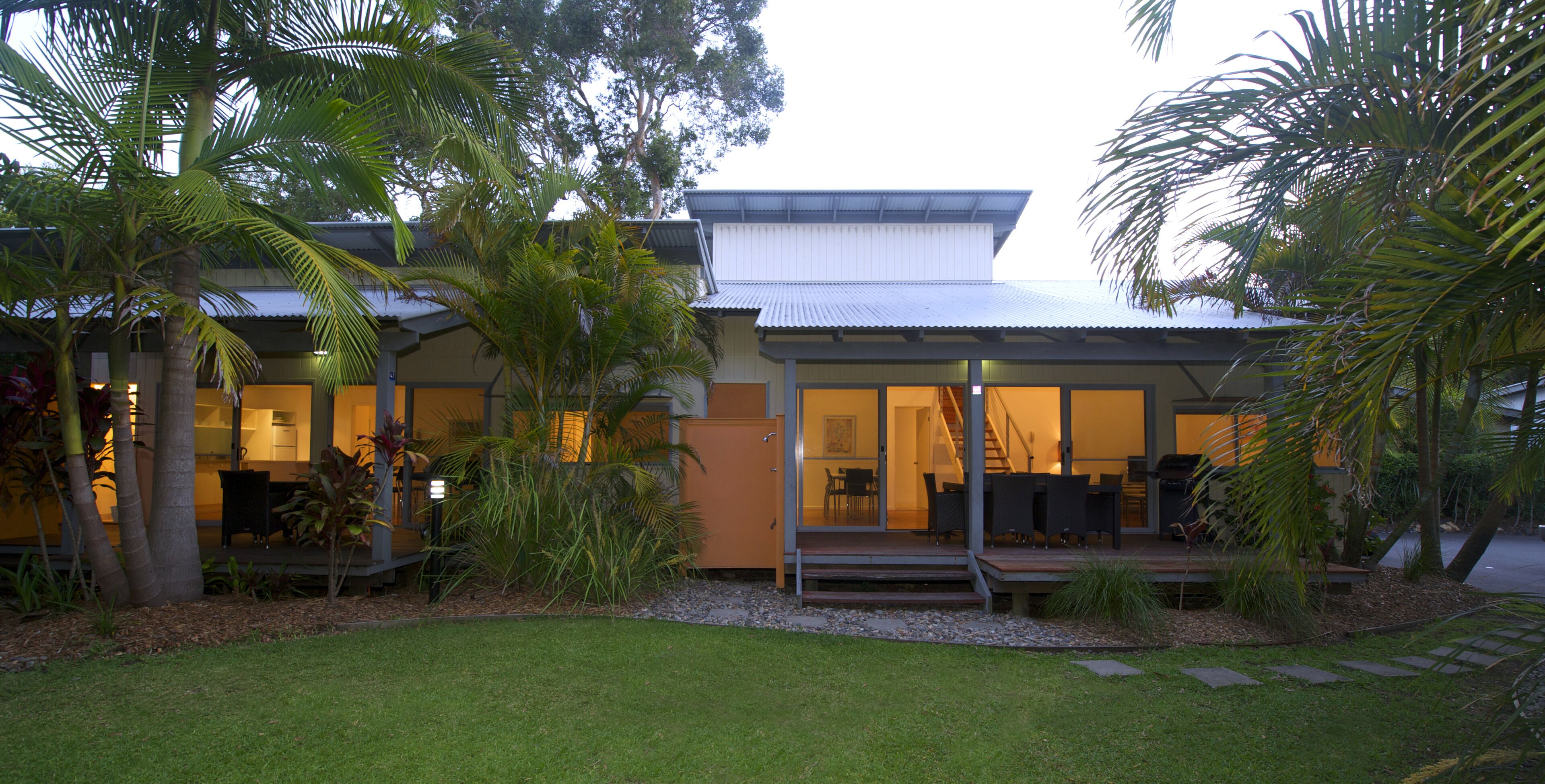 A modern house with a covered porch, a dining area, and a staircase leading to the upper floor.
