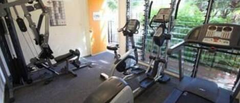 Uma academia com equipamentos de cardio, aparelhos de musculação e esteira.