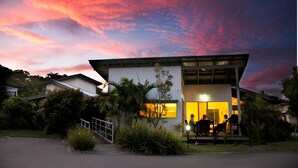 A modern building with a flat roof and large windows, surrounded by greenery. - Mobys Beachside Retreat (Boomerang Beach)