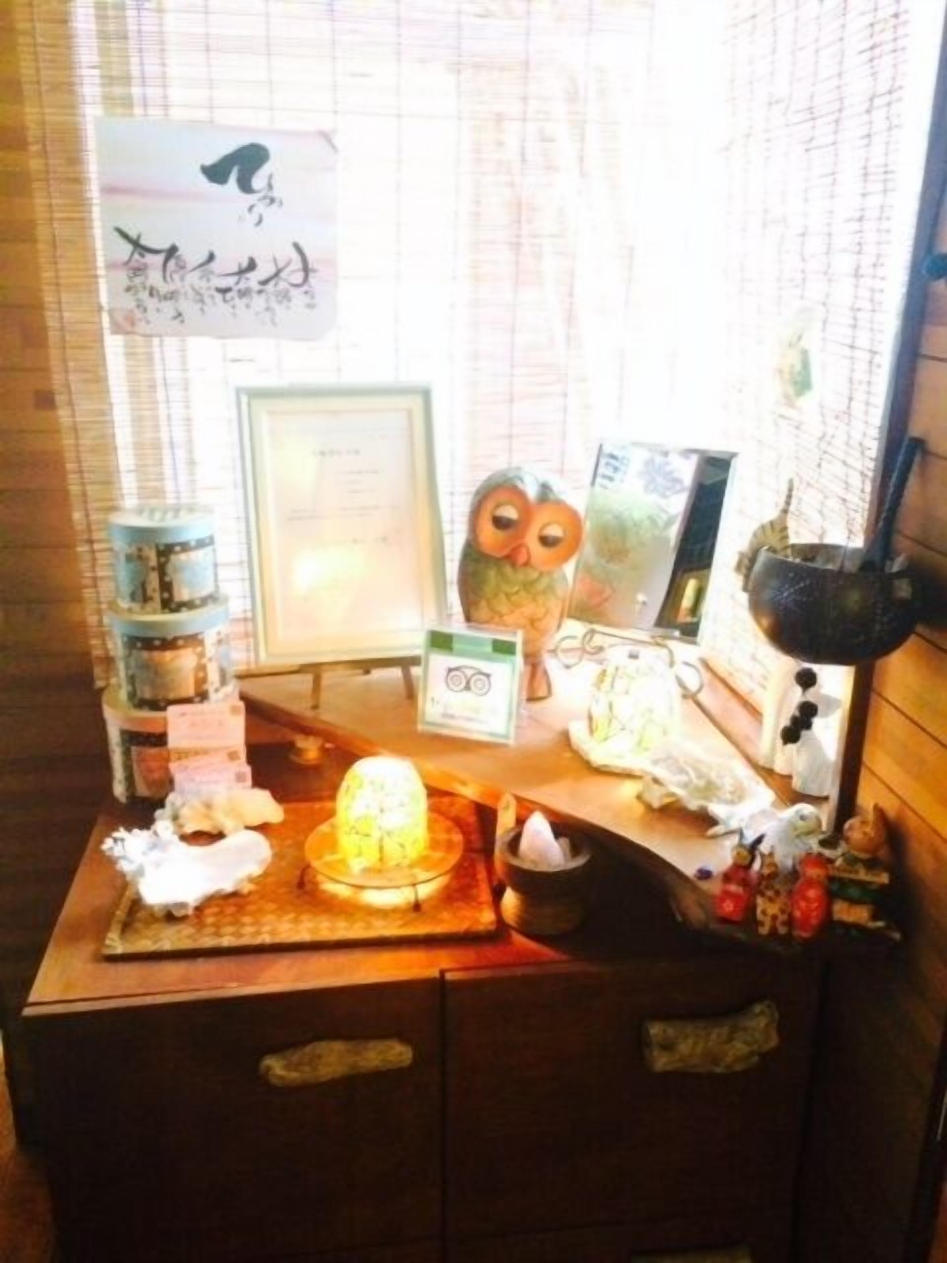 A wooden desk with a framed certificate, a small owl figurine, and various decorative items.