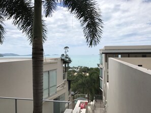 A modern building with a balcony overlooking a beach and the sea.