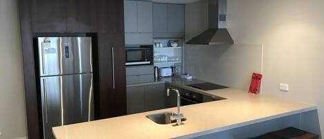 Una cocina moderna con electrodomésticos de acero inoxidable, armarios grises y una isla central con pileta.