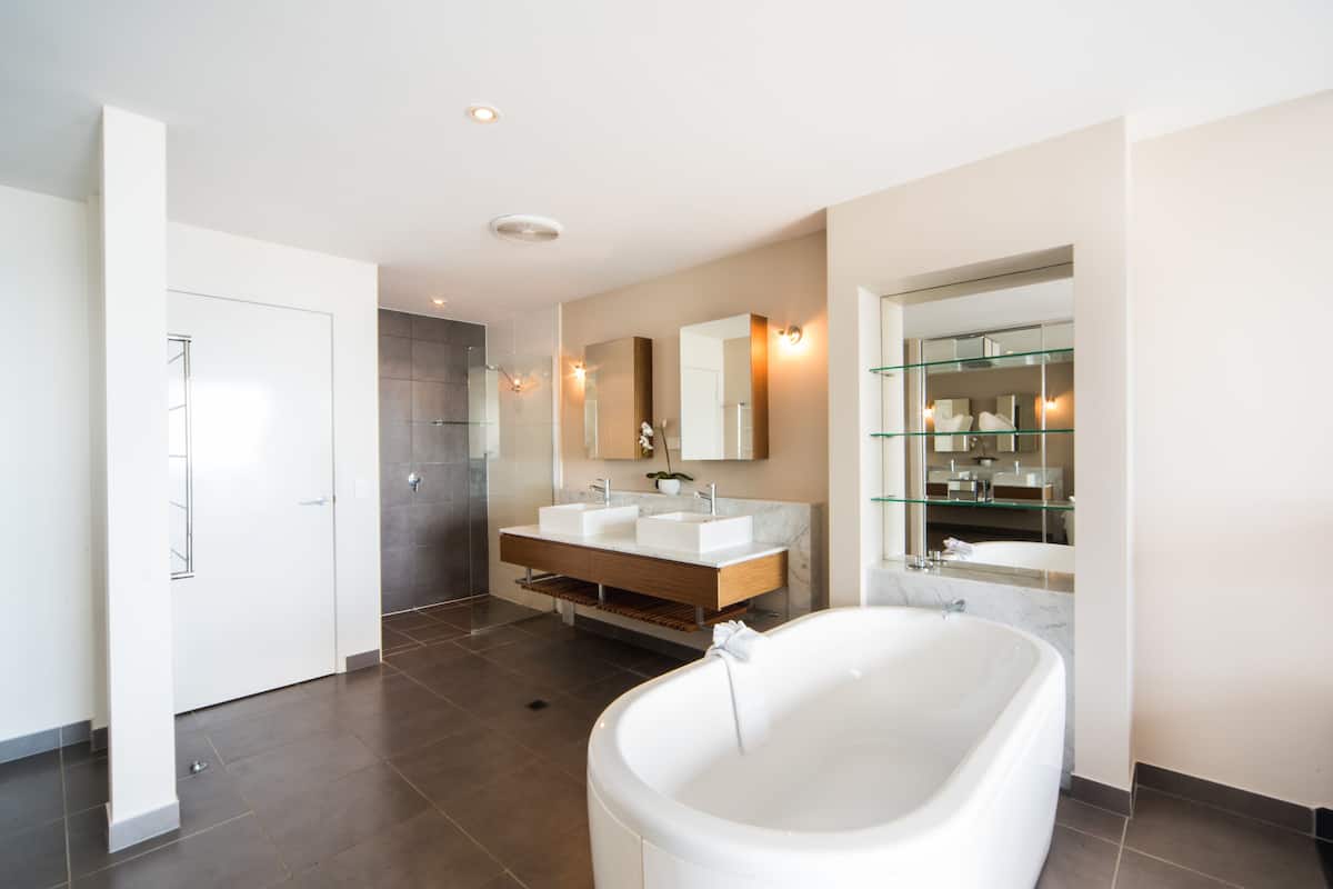 Une salle de bain moderne avec une baignoire sur pieds, deux vasques, une douche à l’italienne et un grand miroir.