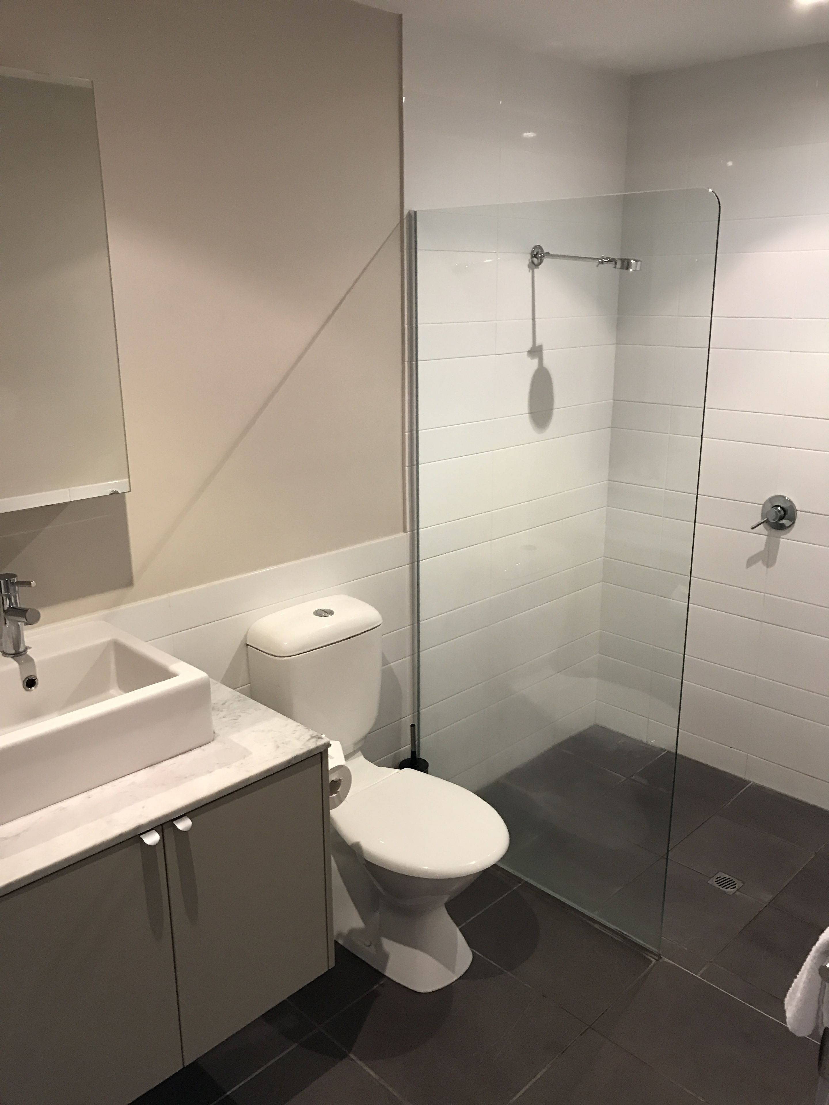 Un bagno moderno con cabina doccia in vetro, un water bianco e un lavabo con piano in marmo.