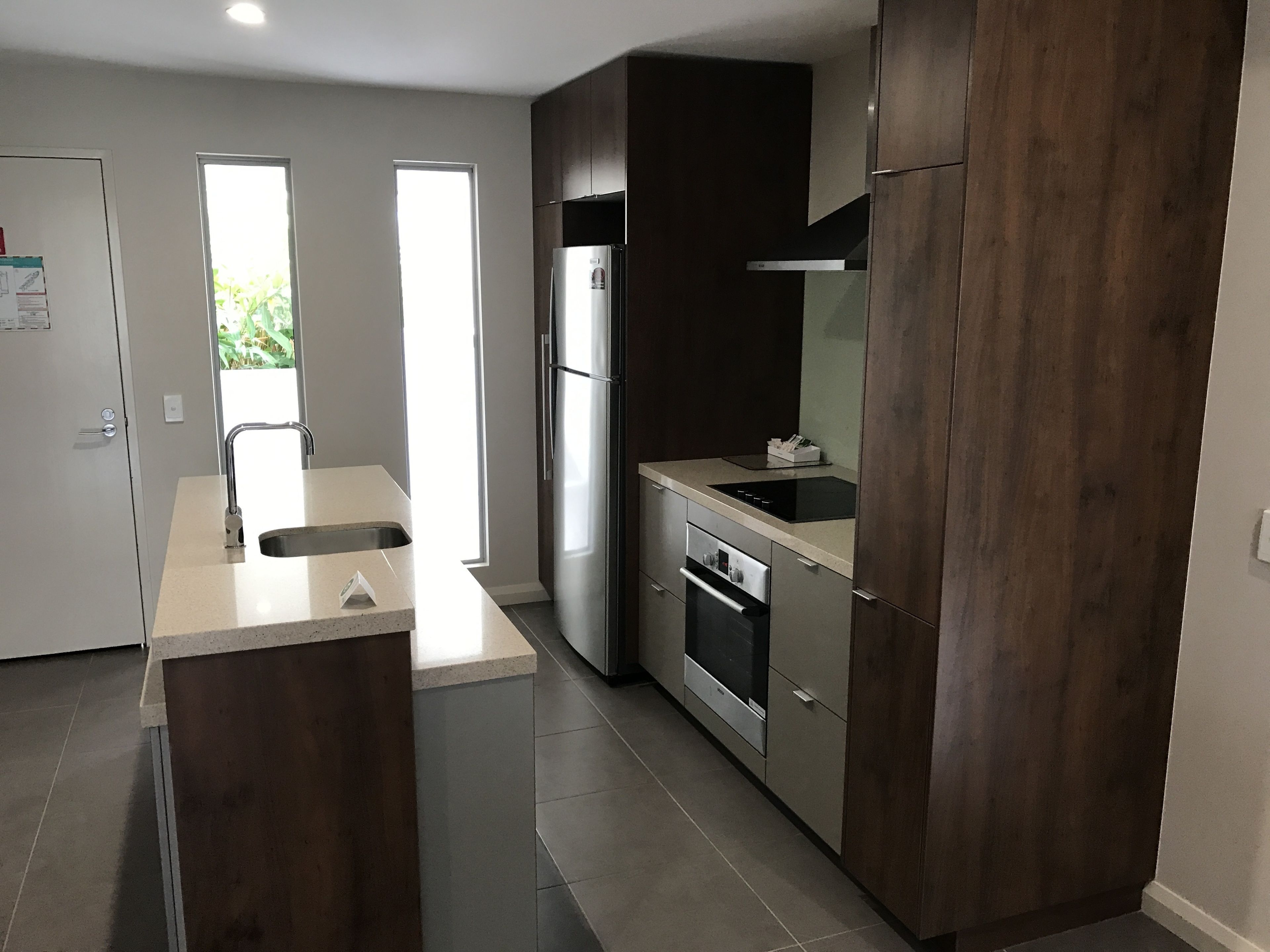 Una cocina moderna con una isla central, electrodomésticos de acero inoxidable y muebles de madera oscura.