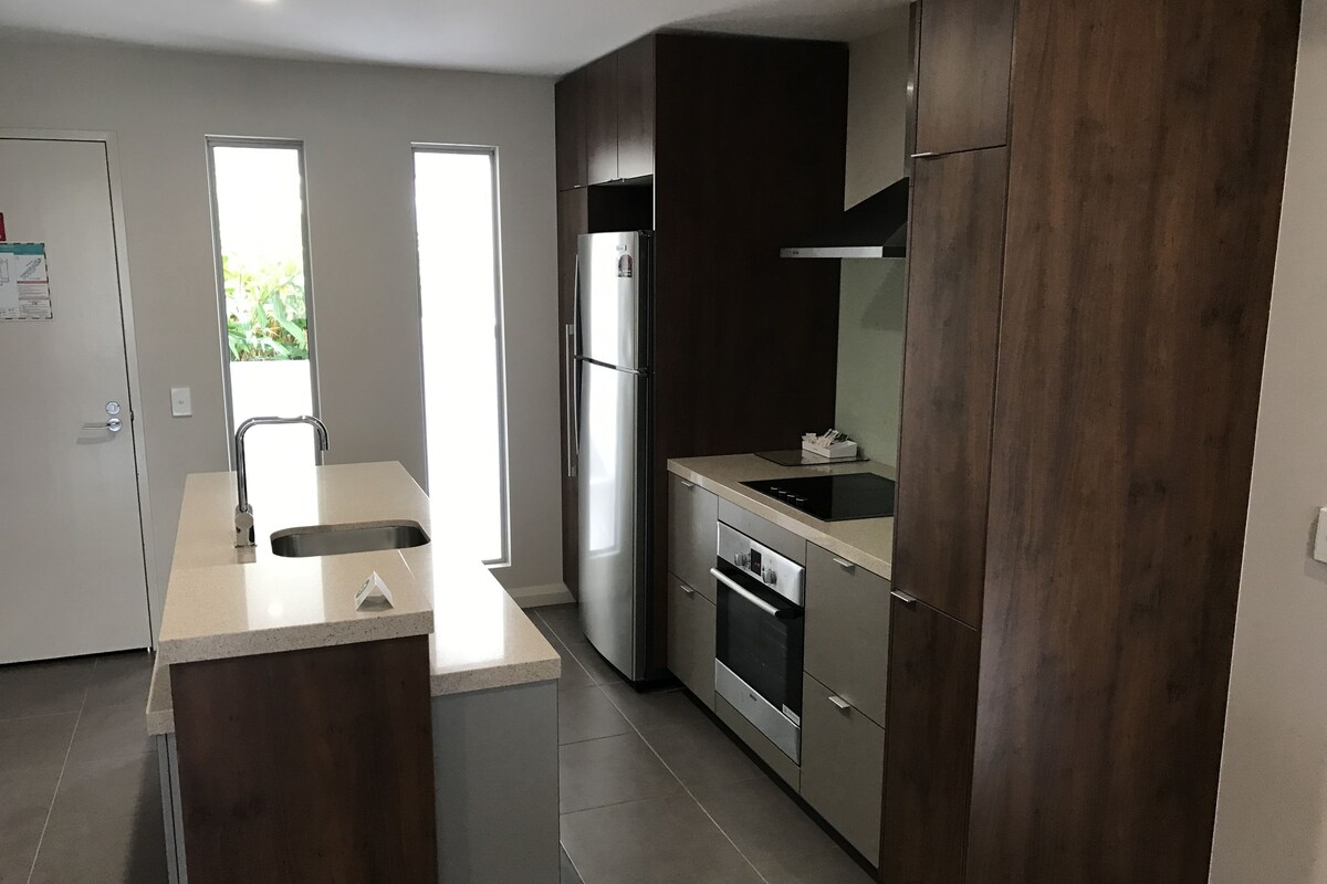 A modern kitchen with a central island, stainless steel appliances, and dark wood cabinetry.