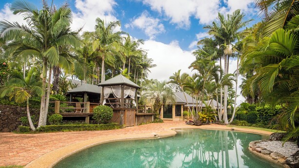 A resort with a swimming pool, palm trees, and a gazebo. - Abbie's Byron Bay Villa (Ewingsdale)