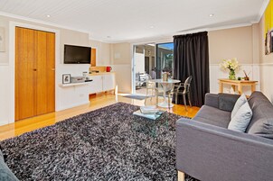 Una sala de estar moderna con un sofá gris, una mesa de centro y un televisor montado en la pared.