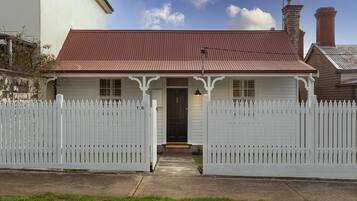 A two-story house with a red roof and white picket fence.
