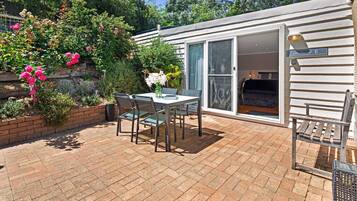 A patio with a table and chairs, surrounded by a brick wall and lush greenery.
