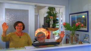 A reception desk with a computer, a vase with flowers, and a framed picture on the wall. - Bermagui Motor Inn (Bermagui)