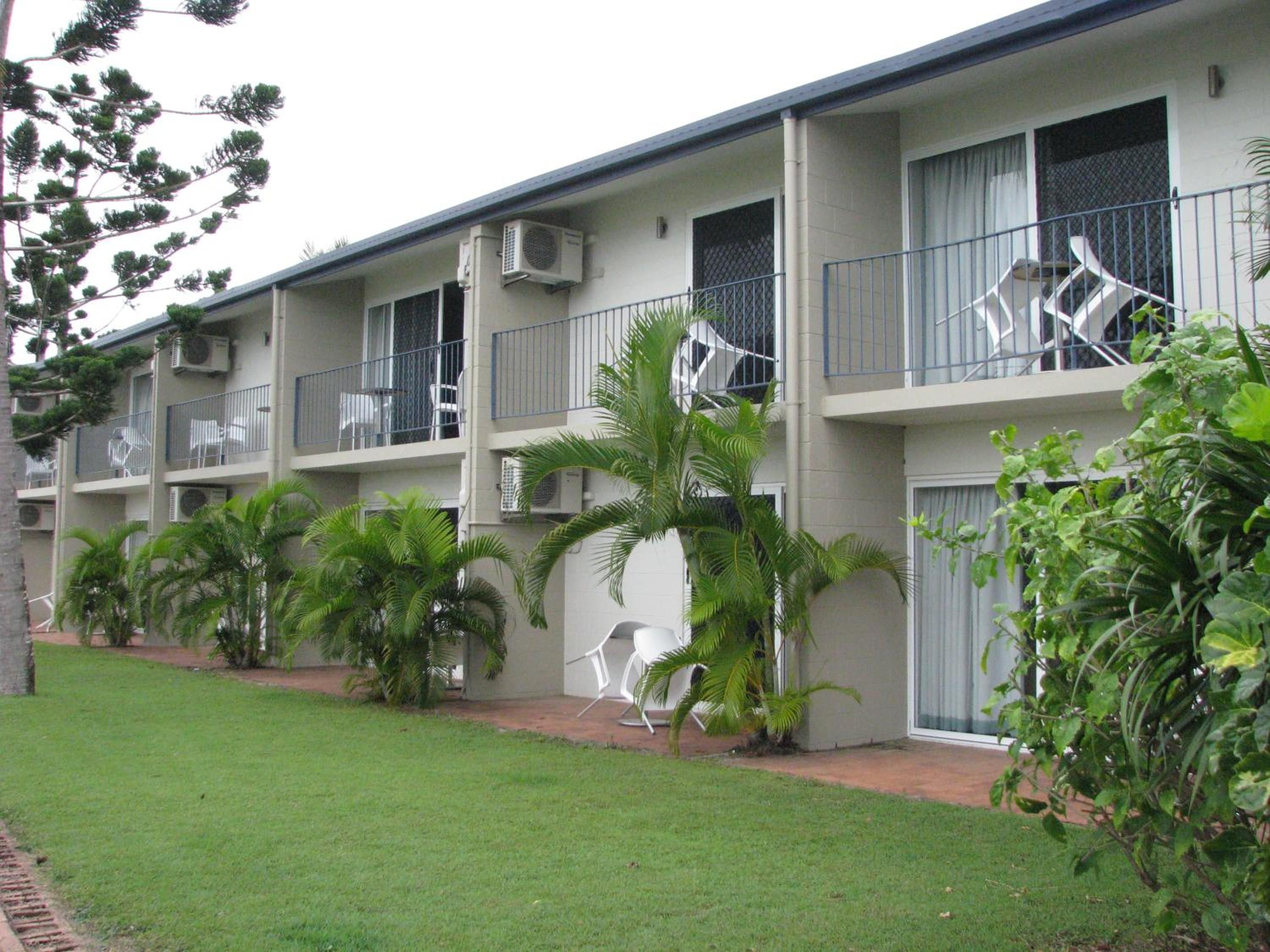 Un edificio de varios pisos con balcones, unidades de aire acondicionado y mobiliario exterior.