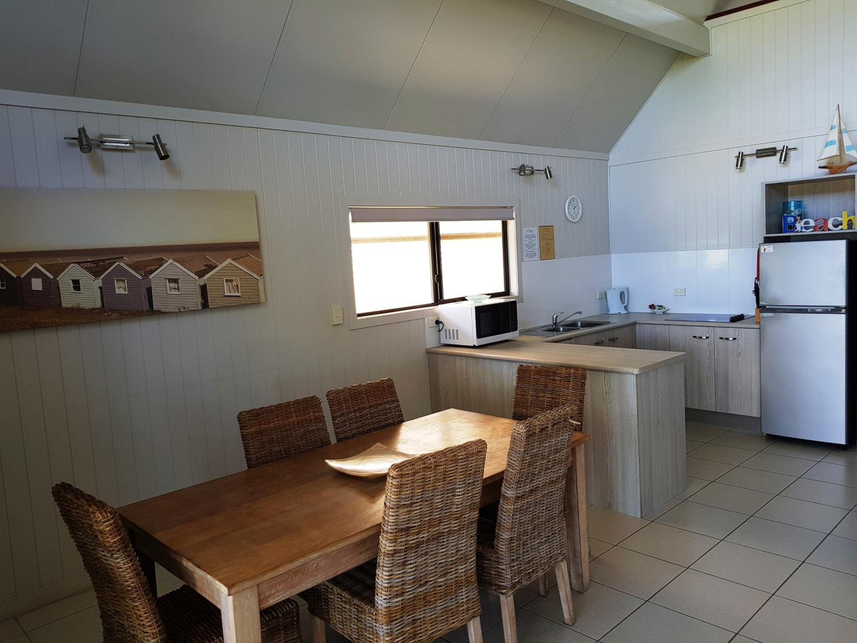 A compact kitchen with a dining area, featuring a microwave, sink, and refrigerator.