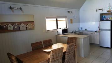 A compact kitchen with a dining area, featuring a microwave, sink, and refrigerator.