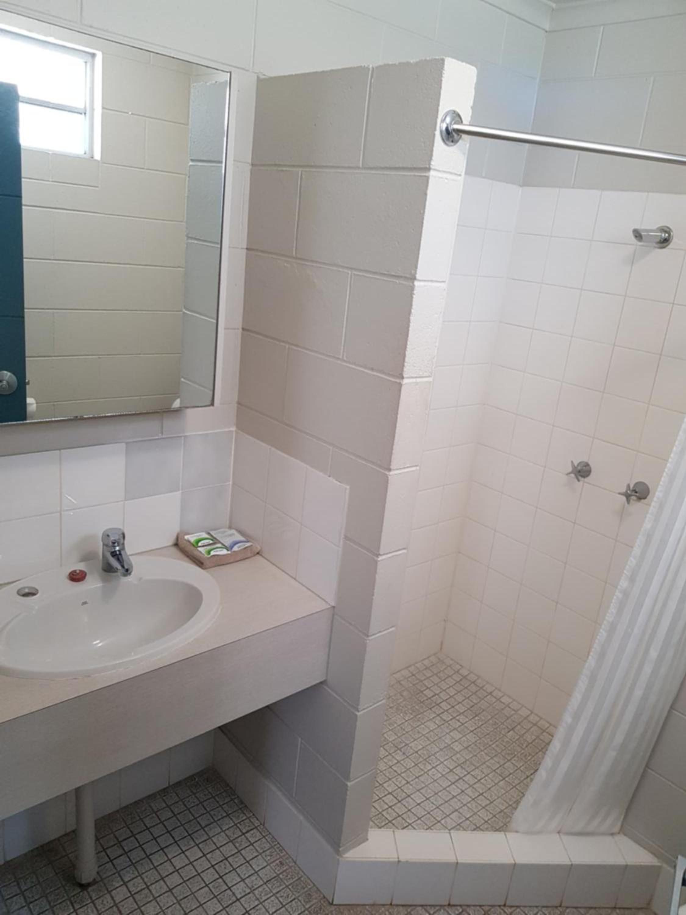 A bathroom with a white sink, mirror, and shower area.