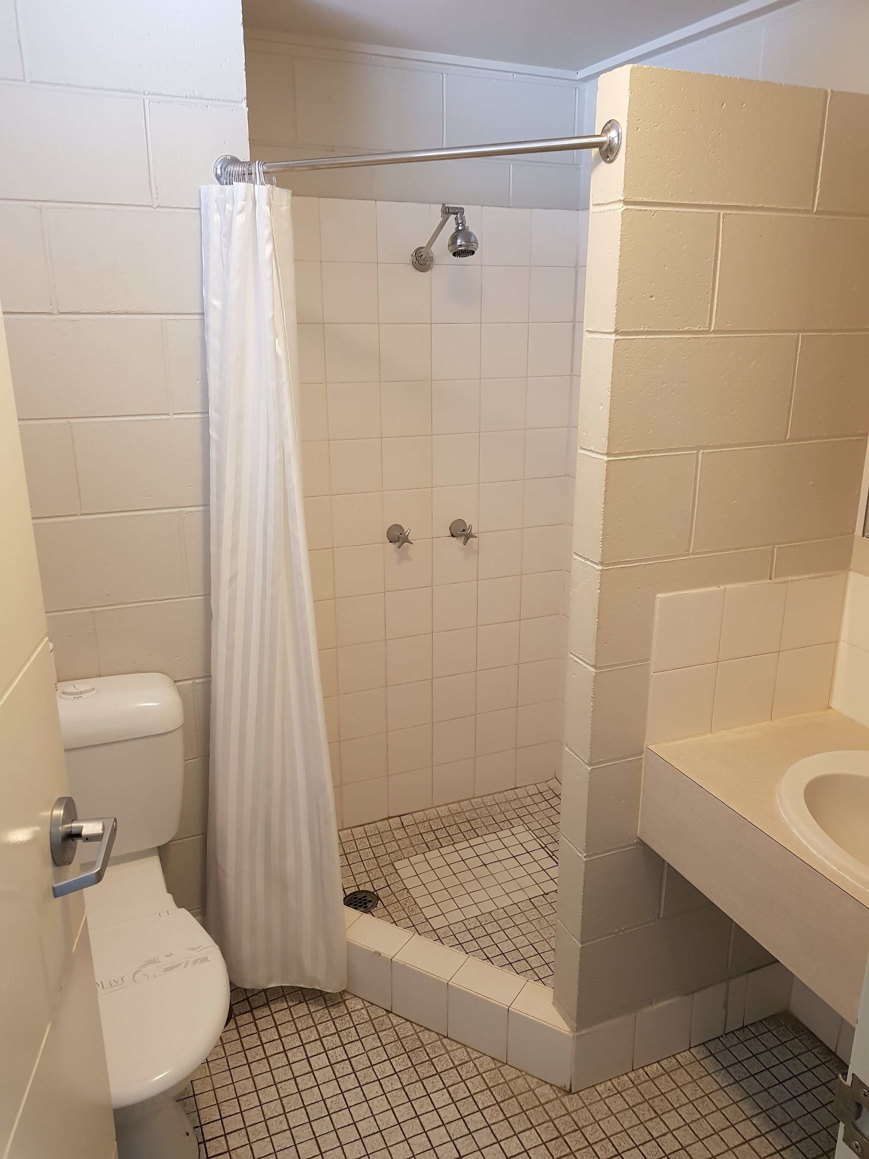 A bathroom with a shower, toilet, and sink.